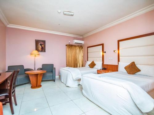 Una habitación de hotel con dos camas y un escritorio. en Denis Hotel - Abuja, en Abuja
