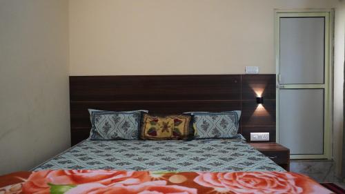 a bedroom with a bed with a wooden headboard and pillows at Hari Om Guest House in Narendranagar