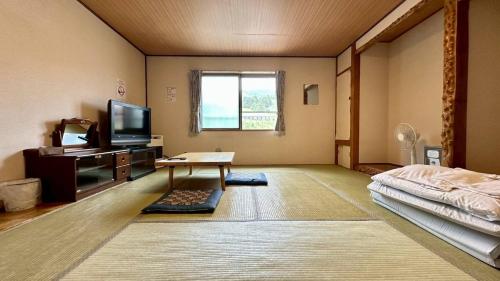 a large room with a bed and a television at ふる郷荘Furusato Furano in Furano