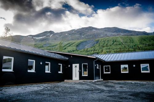 a black building with mountains in the background at Kittelfjäll Vandrarhem in Kittelfjäll
