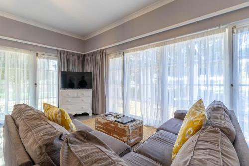 a living room with a large couch and large windows at Whale Rock Luxury Lodge in Hermanus