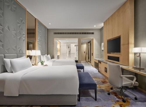 a hotel room with two beds and a television at The Azure Ningbo, Vignette Collection in Ningbo