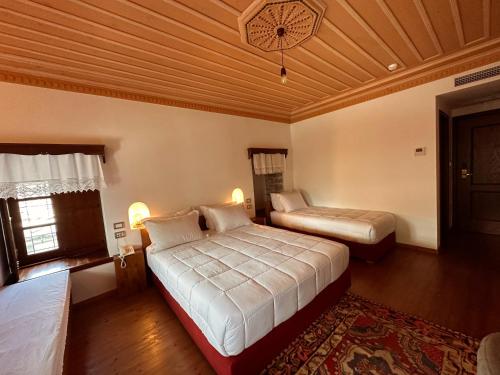 a bedroom with two beds and a wooden ceiling at Kalemi Twin Boutique Hotel in Gjirokastër