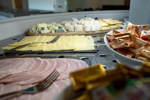 a grill with cheese and meats and a plate of food at Le Pré du Lac in Saint-Jorioz
