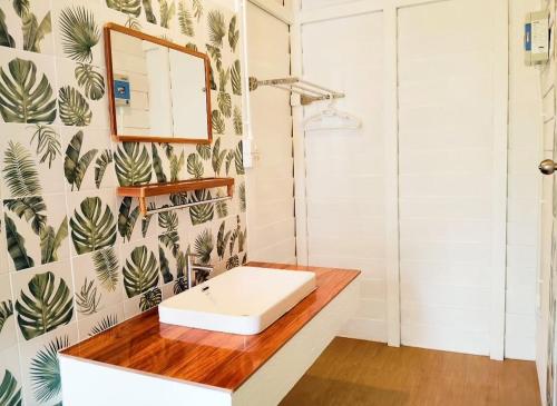 a bathroom with a white sink and a mirror at Koh Phaluai beach cottage in Koh Phaluai