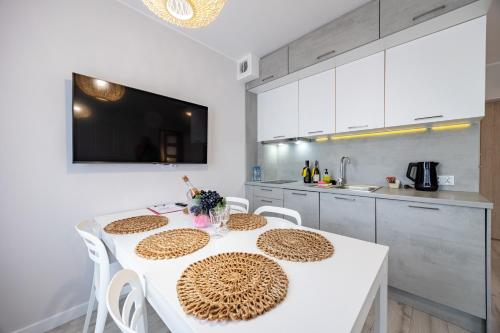 a kitchen with a white table and white cabinets at Apartamenty Rondo in Świnoujście