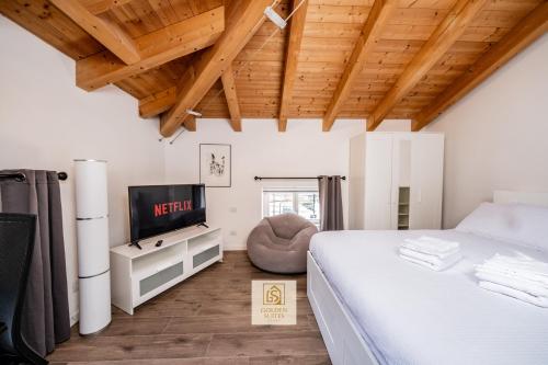 a bedroom with a white bed and a tv at GoldenSuitesItaly I Trento Duomo Suite 1 in Trento