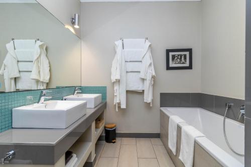 a bathroom with a tub and a sink and a tubermott at Whale Rock Luxury Lodge in Hermanus