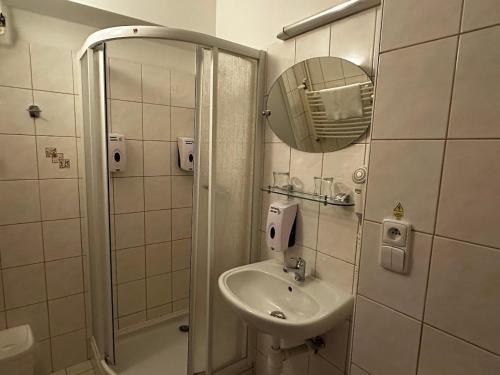 a bathroom with a sink and a shower with a mirror at Hotel Opera in Jaroměřice na Rokytné