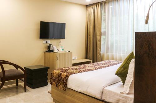 ニューデリーにあるIris Suites Kalkajiのベッドとテレビがあるホテルの部屋