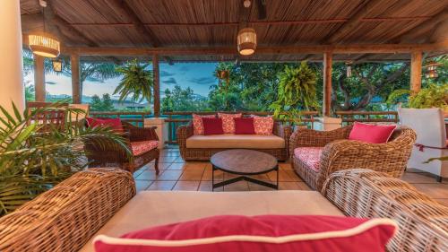an outdoor patio with wicker chairs and a table at Shanti Ghar Guest House in Tamarin