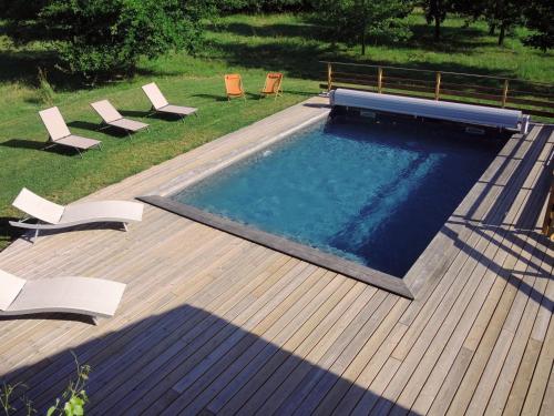 a swimming pool on a deck with chairs around it at En joia ! in Teyssode
