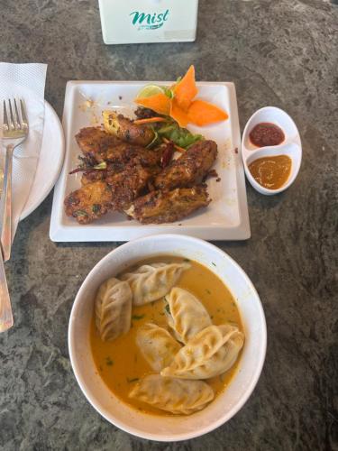 einen Tisch mit einer Schüssel Suppe und einem Teller Essen in der Unterkunft Heranya Taleju in Kathmandu