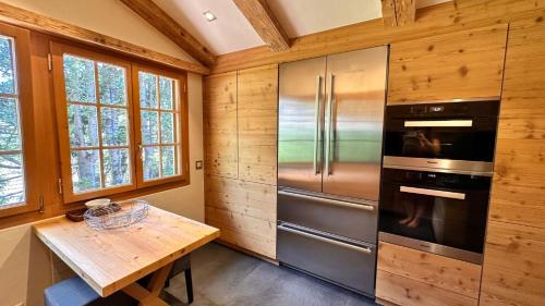 a kitchen with a stainless steel refrigerator and a table at Cozy Gstaad Chalet With Modern Touch in Gstaad