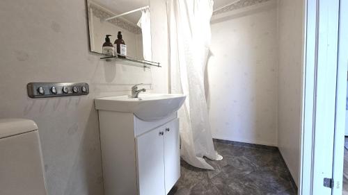 une salle de bain blanche avec un lavabo et un miroir dans l'établissement Cottage near sea, art & fishing villages on Tjorn, à Klövedal