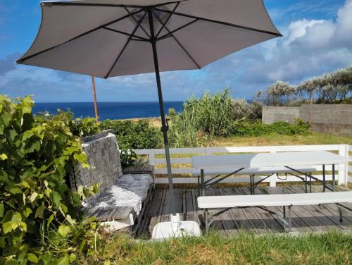 a patio with a table and an umbrella at Casa dos Fenais in Praia da Graciosa