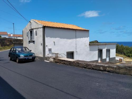 a blue car parked in front of a white building at Casa dos Fenais in Praia da Graciosa