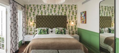 a bedroom with a bed with a green headboard at Cape Cadogan Boutique Hotel in Cape Town