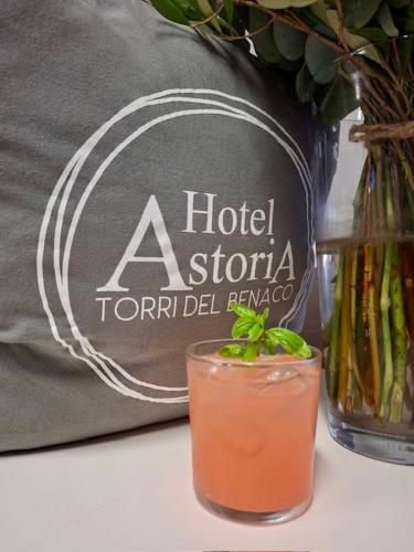 a drink in a glass next to a hotel astoria torillizona pillow at Hotel Astoria in Torri del Benaco