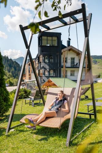 a woman laying on a swing in the grass at Turmchalet Adults Only in Braies