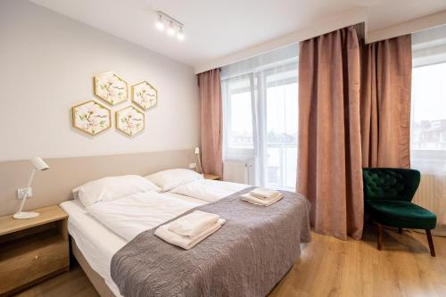 a bedroom with a bed and a chair and a window at Apartamenty Rondo in Świnoujście