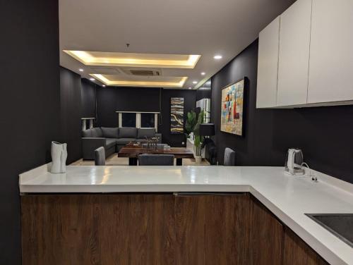 a kitchen with a counter top and a living room at Elysium Executive Hotel Serviced Apartments Facing Centaurus Mall Islamabad in Islamabad