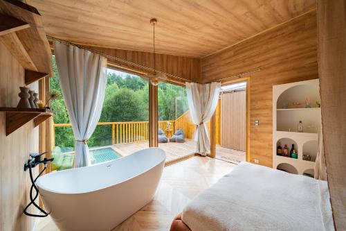 a bathroom with a tub and a bed and a balcony at Nowoczesne Domki na Drzewie - Kołobrzeg - Sauna - PolanaGlamp in Nieżyn