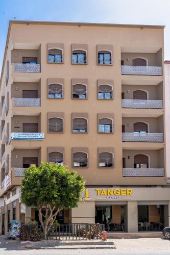 a large tan building with a tree in front of it at Appart hotel tanger in Dakhla