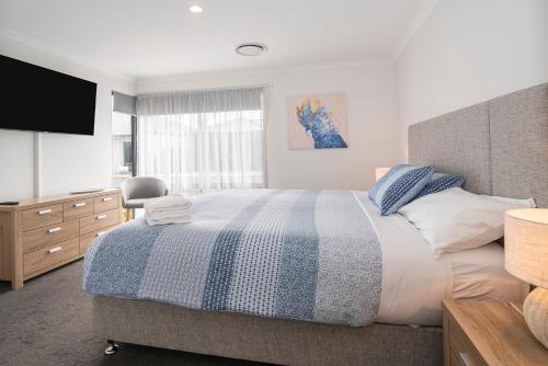 a bedroom with a large bed and a television at Pearl Mews - Heart of Busselton in Busselton