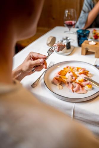 a person eating food on a table with a plate of food at Turmchalet Adults Only in Braies