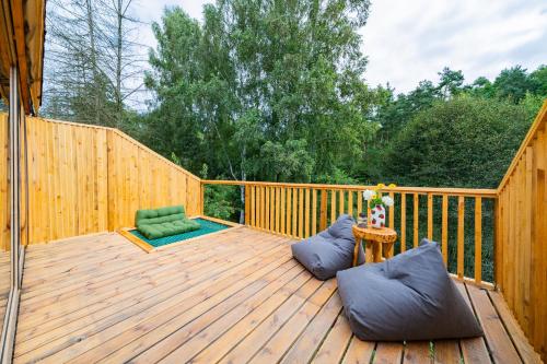 a wooden deck with a chair and a table at Nowoczesne Domki na Drzewie - Kołobrzeg - Sauna - PolanaGlamp in Nieżyn