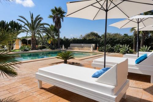 a pool with two white lounge chairs and an umbrella at Tranquil Haven in Ibiza City, 1254 in Sant Francesc de s'Estany