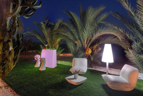 three chairs and a lamp on a lawn with palm trees at Tranquil Haven in Ibiza City, 1254 in Sant Francesc de s'Estany