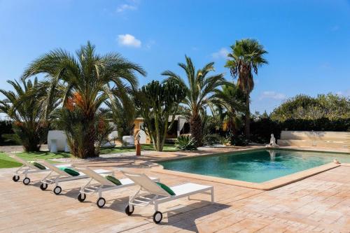 a swimming pool with lounge chairs and palm trees at Tranquil Haven in Ibiza City, 1254 in Sant Francesc de s'Estany