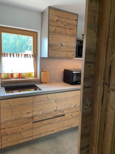 a kitchen with wooden cabinets and a microwave at Haus Bergliebe in Winkl Reichenau