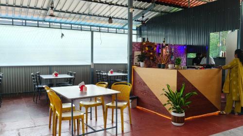 a restaurant with tables and yellow chairs and a counter at De Orchid Resort in Agonda