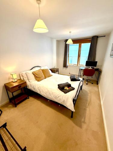 a bedroom with a bed and a desk with a laptop at Harbourside Apartment in Bristol in Bristol