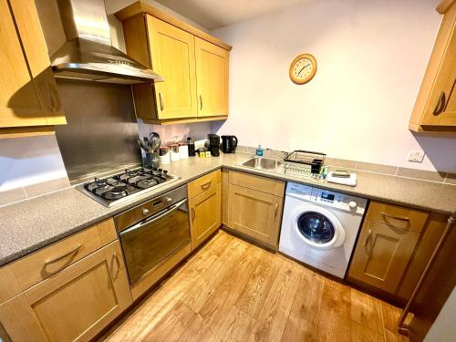 a kitchen with wooden cabinets and a washing machine at Harbourside Apartment in Bristol in Bristol