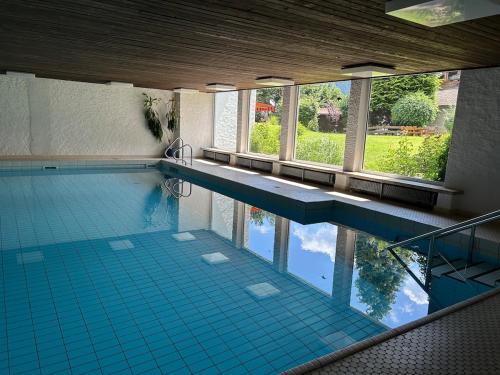 a large swimming pool with blue tile floors and windows at Gemütliche Wohnung mit Bergblick und Terrasse in Obermaiselstein