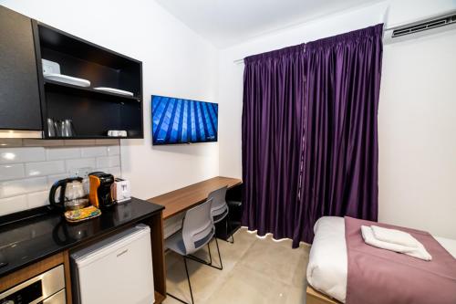 a hotel room with a bed and a desk and purple curtains at New Luxury 2 Single Bed Studio Apartment- BV3 in St Paul's Bay