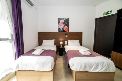 two beds in a hotel room with two bedsitures at New Luxury 2 Single Bed Studio Apartment- BV3 in St Paul's Bay