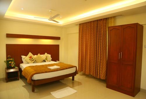 a bedroom with a large bed and a cabinet at Dhanunjayas Luxury Hotel in Hosūr