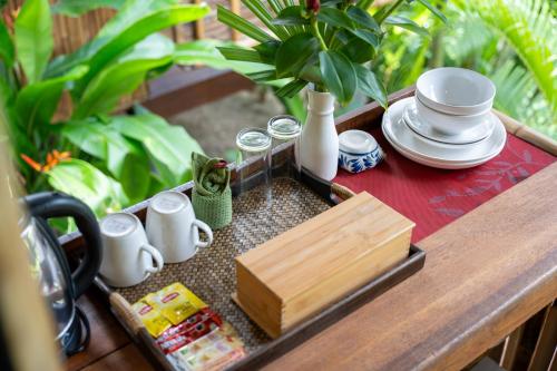 a table with a tray with cups and plates on it at Bamboo Bay Eco Resort in Srithanu