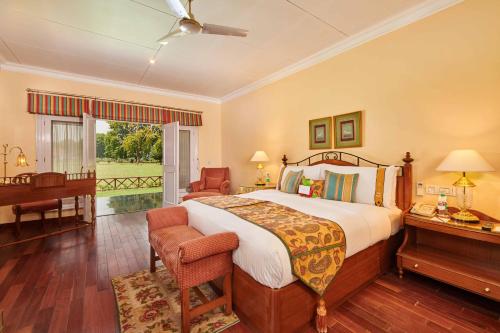 a bedroom with a large bed and a piano at The LaLit Grand Palace Srinagar in Srinagar