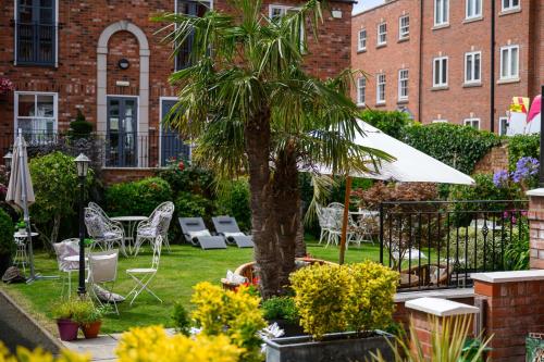 a palm tree in a yard with chairs and an umbrella at Darwins Townhouse in Shrewsbury