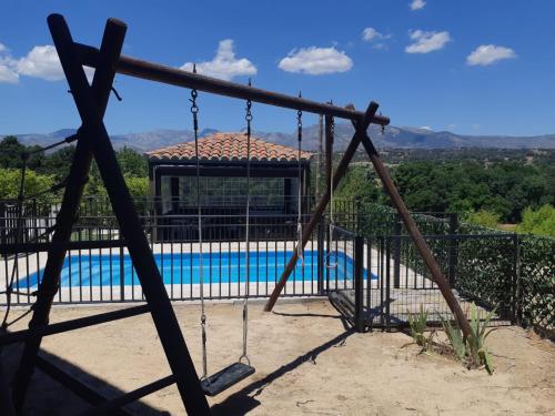 a swing in front of a swimming pool at Casa Rural La Casita Roja in Burgohondo