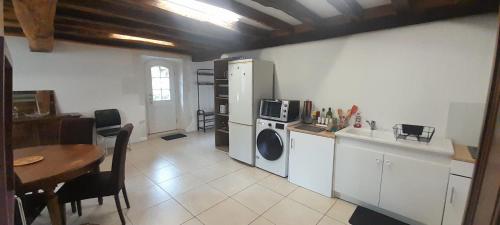a kitchen with a table and a refrigerator and a table and chairs at L'ancienne boulangerie du Grand Verger 7 pers in Déols