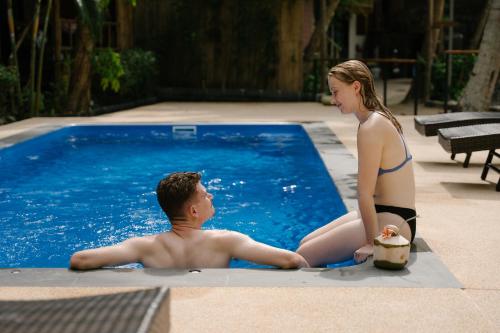 a man and a woman sitting next to a swimming pool at Coconut Bay Eco Resort in Srithanu