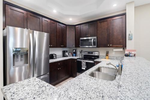 a kitchen with wooden cabinets and a stainless steel refrigerator at Luxury Oasis - Fresh impovements, Pool & Patio in Cape Coral