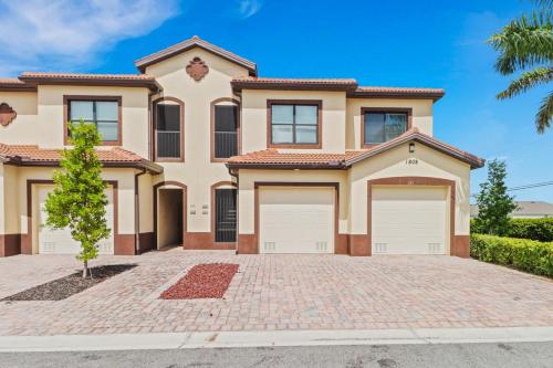 a house with two garage doors on a brick driveway at Luxury Oasis - Fresh impovements, Pool & Patio in Cape Coral